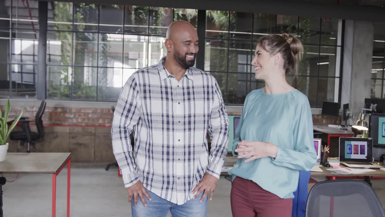 dos diseñadores creativos felices y diversos en discusión en una oficina casual, cámara lenta