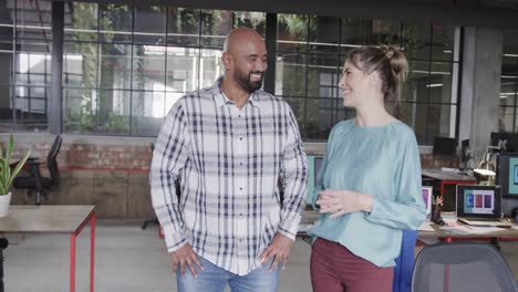 two happy diverse creative designers in discussion in casual office, slow motion