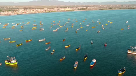 Dolly-in-aerial-view-of-several-yellow-fishing-boats-on-the-shore-of-Tongoy,-northern-Chile