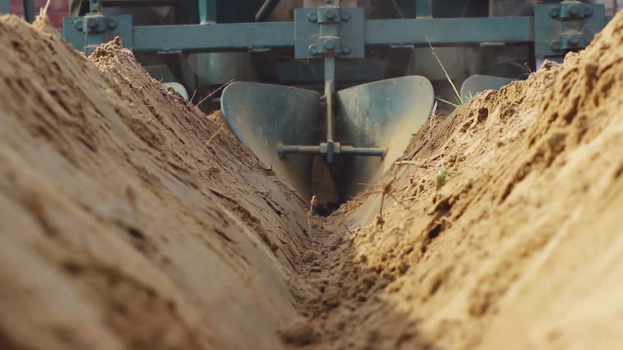 трактор, боронующий почву на ферме, вид с задней стороны с близкого расстояния под низким углом