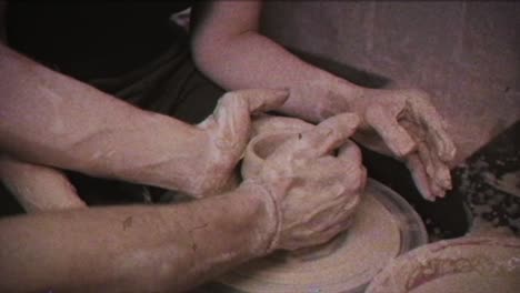 a potter teaches a woman to make clay dishes. a man takes a woman's hands. vintage effect.