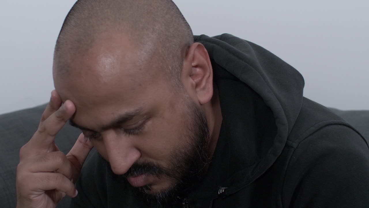 macho de minoría étnica estresado asintiendo mientras se sentaba