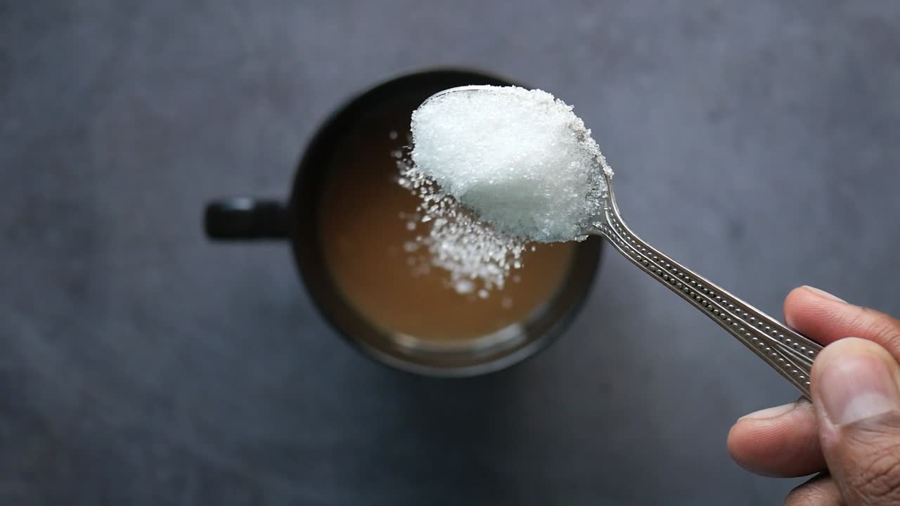 movimiento lento de verter azúcar blanca en una taza de café , vista de arriba ,