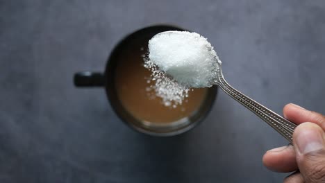 slow motion of pouring white sugar in a coffee cup , top view ,