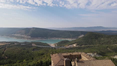 Un-Apacible-Embalse-De-Yesa-Y-Un-Monasterio-De-Leyre-Con-Aterrizaje-De-Drones-Detrás