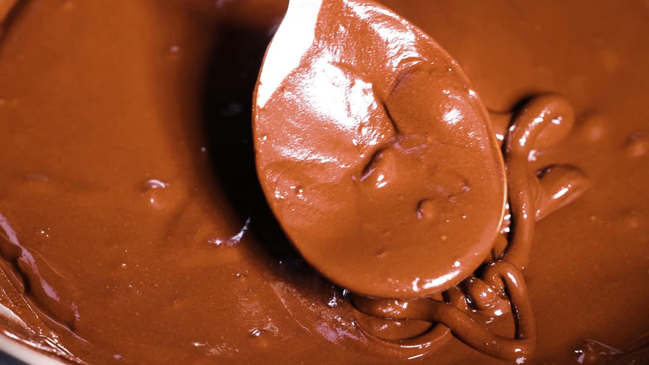 Spoon stirring rich, melted chocolate in bowl