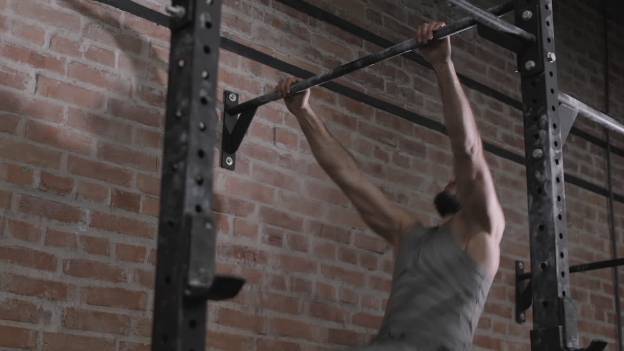 Sporty Man Exercising on Horizontal Bar Indoors