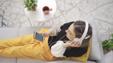 relaxing young woman sitting on sofa at home listening to music and relaxing.