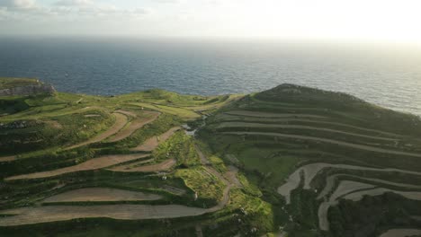 aerial: flying above cliffs towards mediterranean sea in malta during sunset golden hour