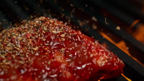 costillas marinadas sazonadas con mezcla de especias, barbacoa en la parrilla entre las llamas - macro y cámara lenta