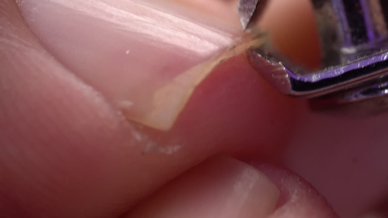 Close up macro view of hand trimming fingernail with metal clipper in vertical shot