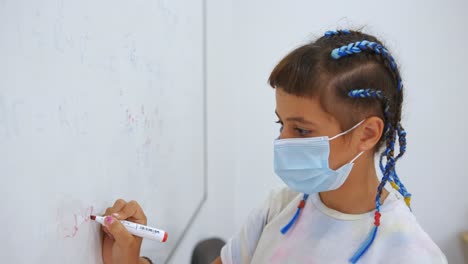 Joven-Estudiante-Con-Mascarilla-Respondiendo-Preguntas-De-Matemáticas-En-Una-Pizarra-Blanca-Con-Marcador-Rojo