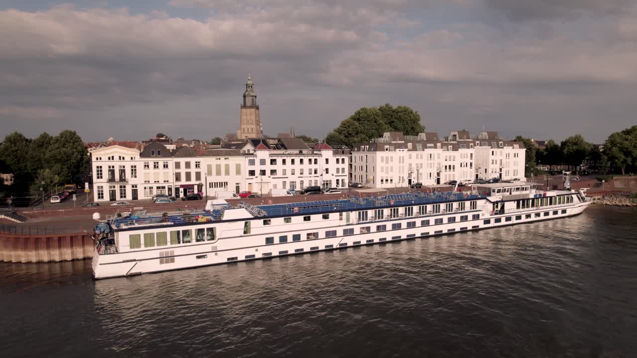 Aerial large tourist river cruise passenger boat Dutch Melody at the IJsselkade boulevard on a sunny day seen from the river IJssel with city countenance behind