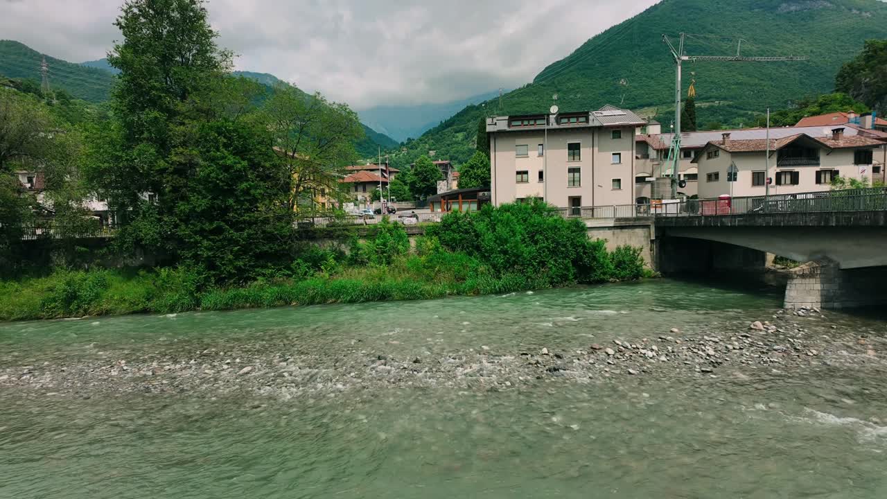 Hyperlapse of Scenic Oglio river flowing through Cividate Camuno with lush green riverbanks and hills in background. Mountainous landscape of Lombardy region during summer afternoon in Italy