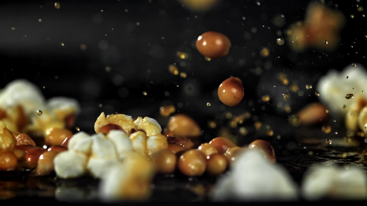 Popcorn Kernels Popping in Slow Motion with Oil Splashes