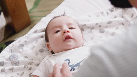 Close-Up-Of-Loving-Father-Playing-With-Newborn-Baby-Son-Lying-On-Bed-At-Home-In-Loft-Apartment