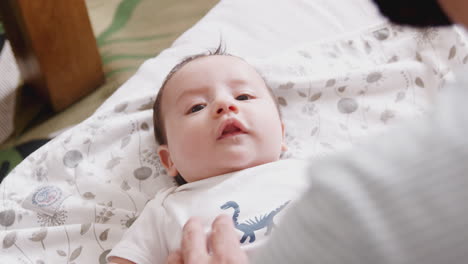 close up of loving father playing with newborn baby son lying on bed at home in loft apartment