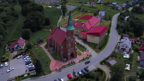 Riesige-Backsteinkirche-Mit-Rotem-Dach-Und-Davor-Stehender-Menschengruppe