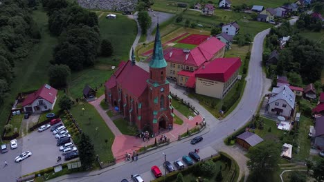 enorme iglesia de ladrillo con techo rojo y un grupo de personas paradas frente a ella