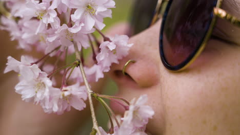 slow motion shot of a woman smelling the cherry blossom petals and smiling in kyoto