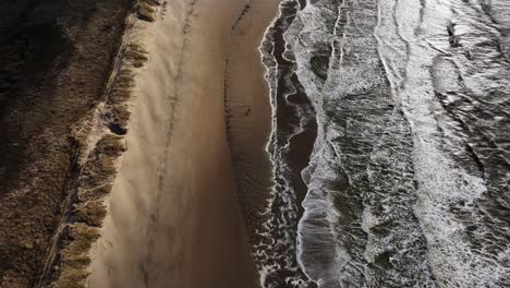 aerial view of a beach with waves and dunes