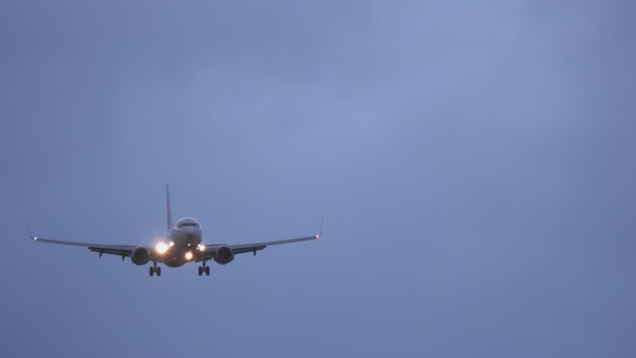An airliner approaches San Diego International Airport at dusk in tricky winds.