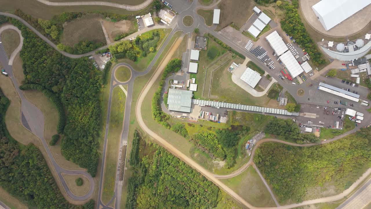Bird’s-eye aerial drone video of Bedford proving grounds motor vehicle testing track with automotive research and car innovation in green England landscape