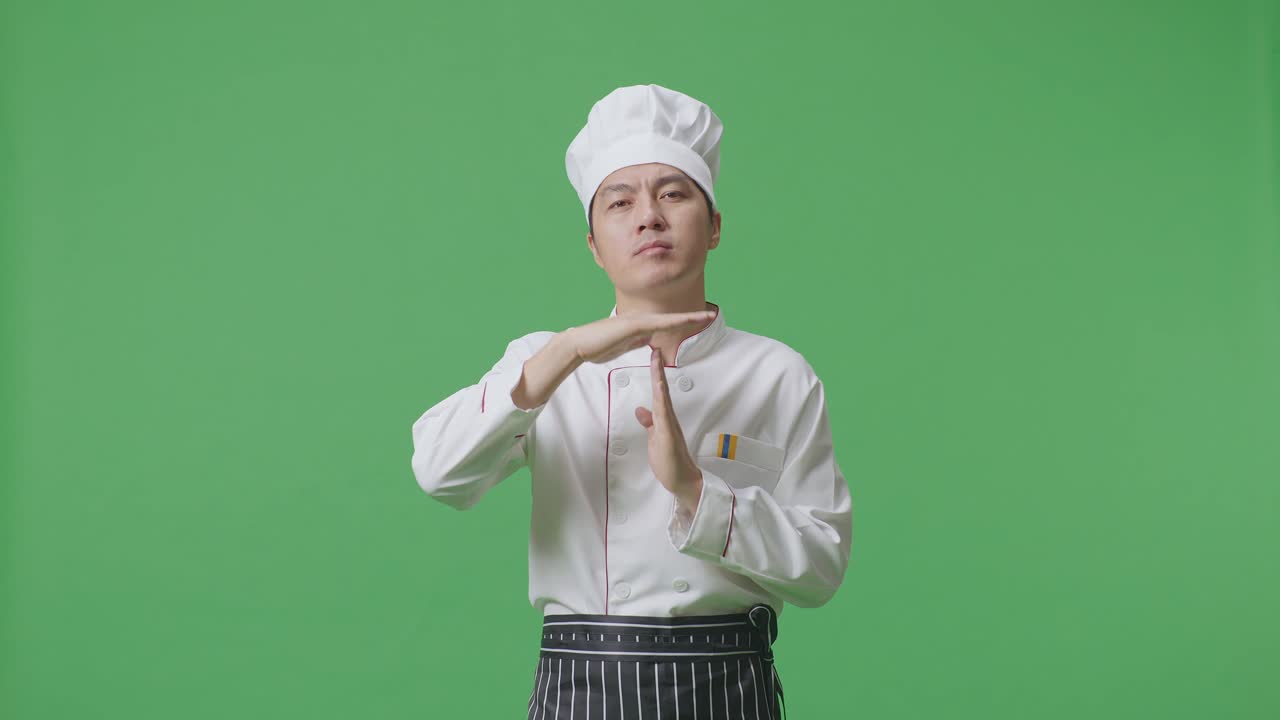 Asian Man Chef Looking At Camera And Showing Time Out Hands Gesture While Standing In The Green Screen Background Studio