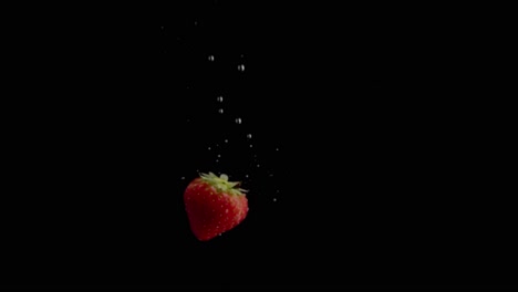 strawberry falling into water super slowmotion, black background, lots of air bubbles, 4k240fps
