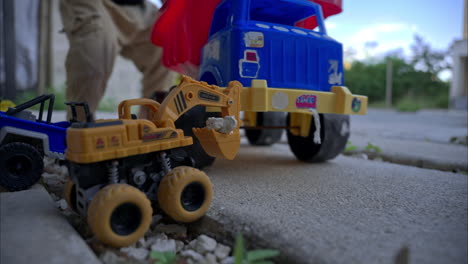 unrecognizable young latin mexican preschooler playing barefooted with his car toys on the sidewalk in the afternoon