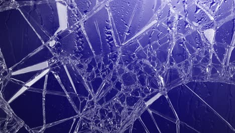 cracked glass with raindrops and pulsating red and blue police lights. abstract background for crime, emergency, danger, or urban drama. dynamic and urgent visual