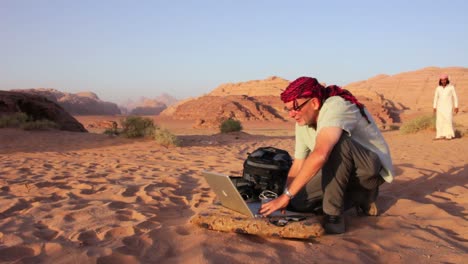 un uomo lavora su un computer portatile nel mezzo del deserto