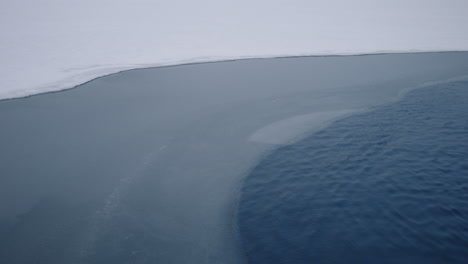 Snow-Covered-Shoreline-In-A-Peaceful-Lake-During-Cold-Winter-Season