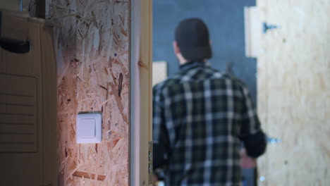 Young-man-turning-on-light-and-entering-home-garage