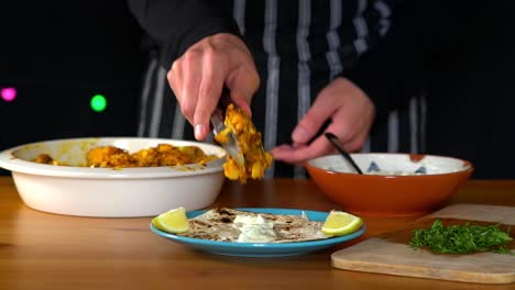 Man-Chef-making-roasted-cauliflower-tacos:-putting-roasted-vegetables-on-top-of-tortilla-bread,-assembling-the-taco