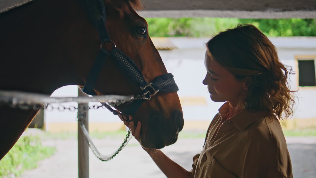 Serene cowgirl caressing horse at paddock closeup. Happy animal enjoy owner love