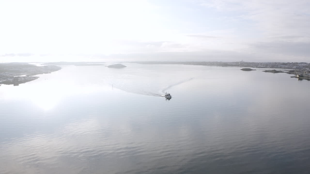 Drone shot of a boat cruising in open ocean water outside Öckerö Island Municipality in Gothenburg archipelago, Sweden.