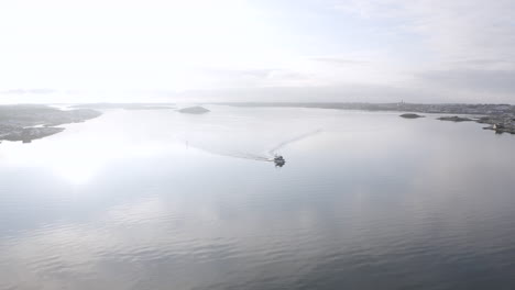 drone shot of a boat cruising in open ocean water outside öckerö island municipality in gothenburg archipelago, sweden.