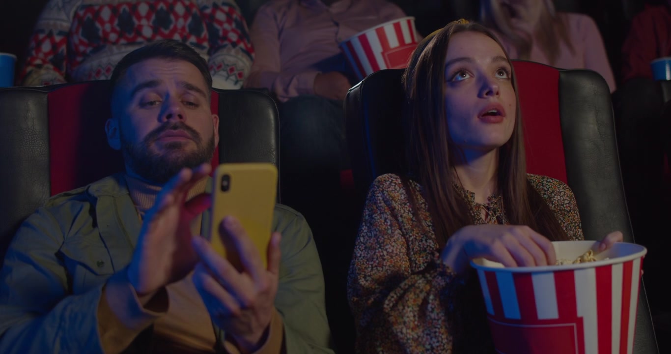Pasangan Muda Duduk di Bioskop dengan Popcorn