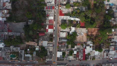 Aerial-birds-eye-overhead-top-down-panning-view-of-car-driving-in-streets-of-town.-Small-and-low-houses-with-flat-roof.-Valladolid,-Mexico