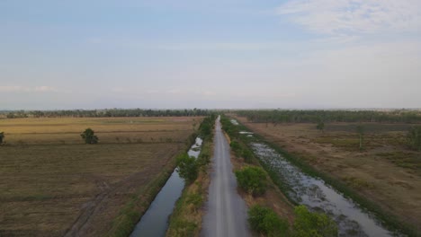 Imágenes-Aéreas-Ascendentes-De-La-Carretera-Con-Canales-En-Pak-Pli,-Nakhon-Nayok,-Tailandia