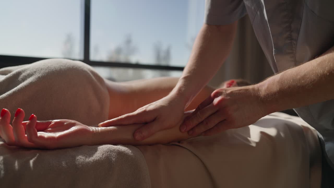 Professionel massør giver armmassage til en kvinde i et spa