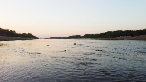 Aerial-view-away-from-a-caraf-with-fresh-water-on-a-rock-in-middle-of-a-river