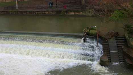 Aspect-of-a-large-river-weir-at-the-Pulteney-Bridge-on-the-River-Avon,-in-the-beautiful-Roman-city-of-Bath,-in-the-English-West-Country