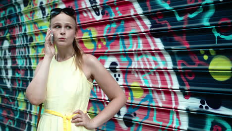 Woman-chatting-on-her-mobile-in-front-of-graffiti