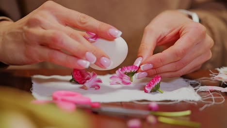 hands gently arranging flower petals on egg for festive natural dyeing ritual
