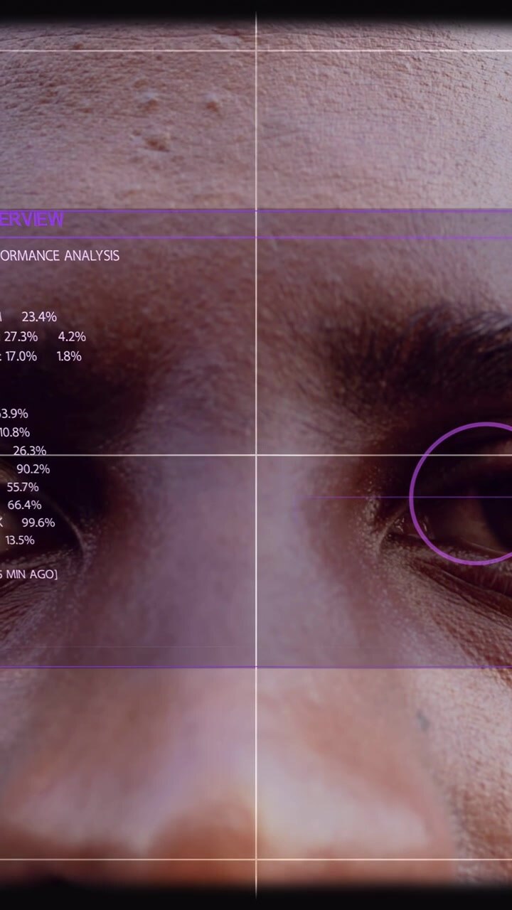Vertical video: Man holding still while HUD slides in, reticle targeting right eye for biometrics