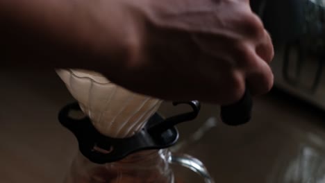 close-up static shot of pre-wetting filter paper with hot water before brewing coffee pour-over