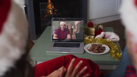 Caucasian-couple-on-video-call-with-young-couple-at-christmas-time