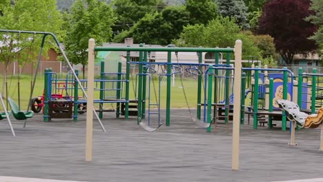 empty city school park with swings swaying in wind on their own no people